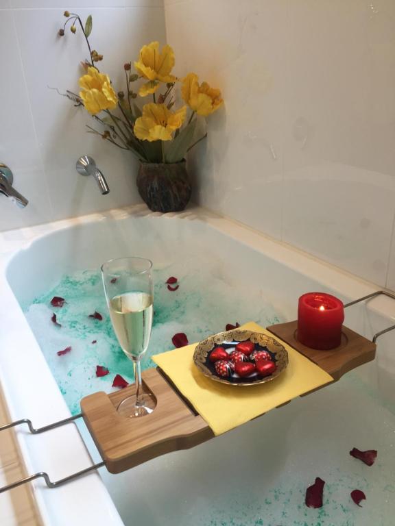 a glass of wine and a plate of food in a bath tub at Garasu Lodge in Gold Coast