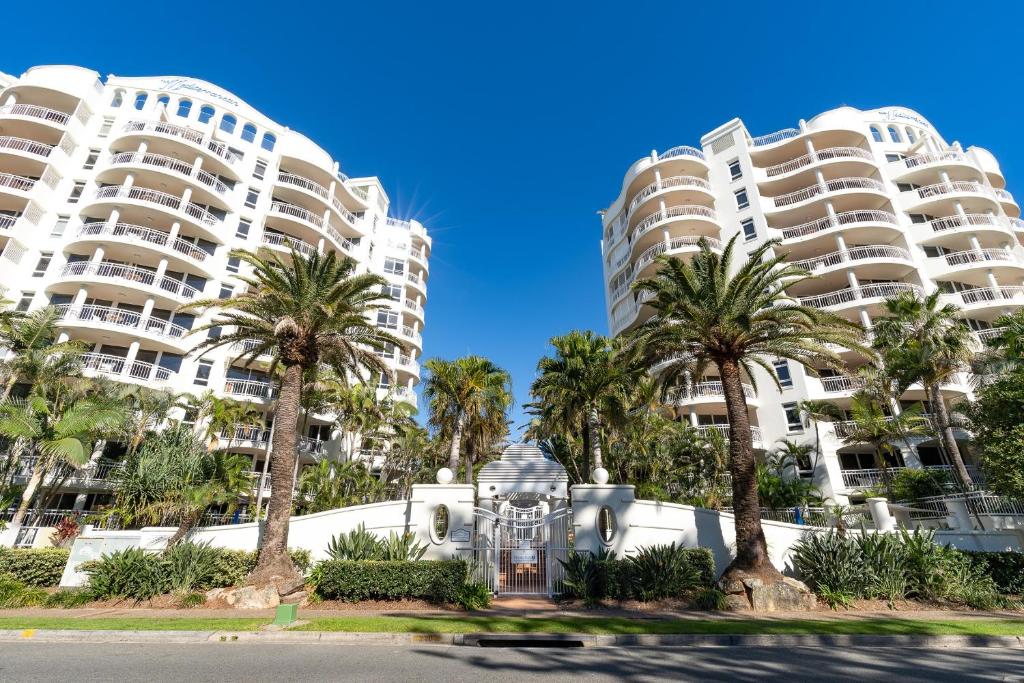 two tall buildings with palm trees in front of a street at ULTIQA Burleigh Mediterranean Resort in Gold Coast