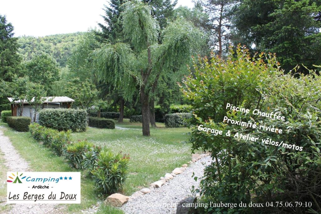 a garden with a tree and a gravel path at Camping Les Berges Du Doux in Colombier-le-Vieux