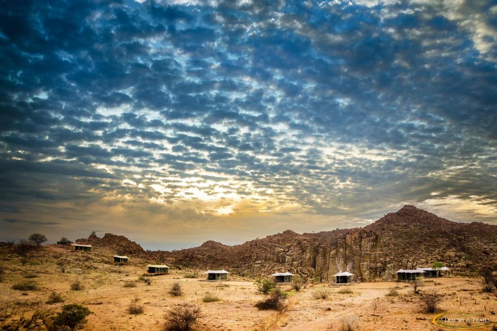 un grupo de chozas en el desierto bajo un cielo nublado en Ozondjou Trails, en Khorixas