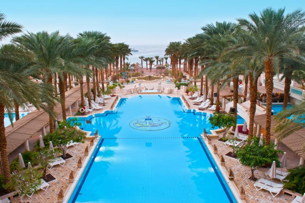 Herods Palace Hotels & Spa Eilat a Premium collection by Fattal Hotels في إيلات: اطلالة جوية على مسبح المنتجع مع النخيل