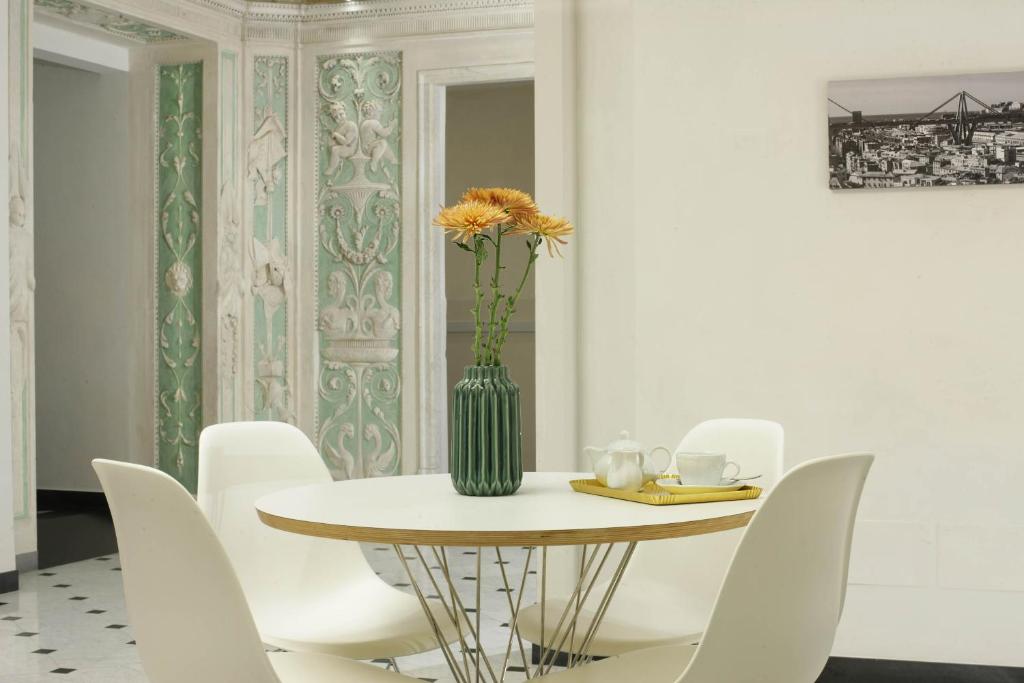 a dining room table with a vase with a flower on it at Hotel Le Nuvole Residenza d'Epoca in Genoa