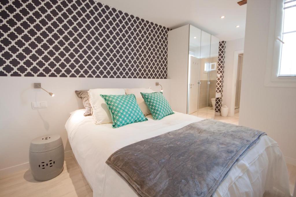 una camera da letto con un grande letto bianco con cuscini blu di Loft de lujo a pasos del prado a Madrid