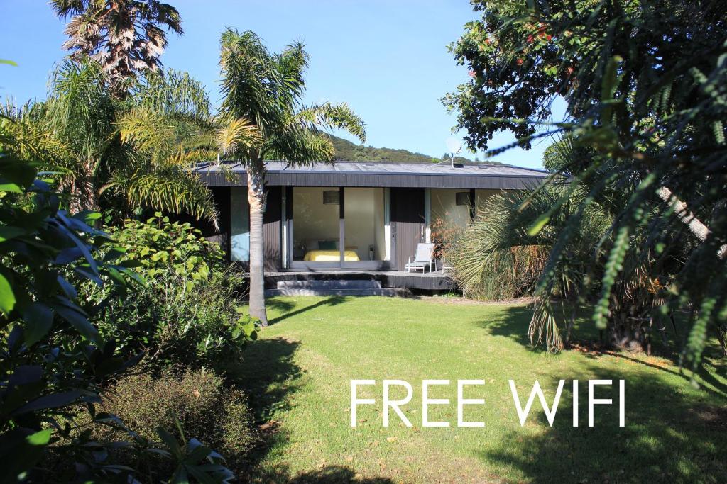 a home with a free wifi sign in front of a yard at Hot Water Beach Bure Wera in Hotwater Beach