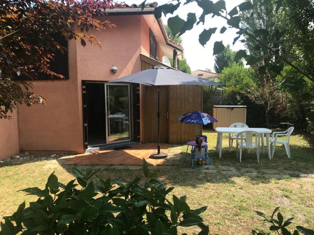 a patio with an umbrella and a table and chairs at Maison de vacance Hourtin Lac in Hourtin