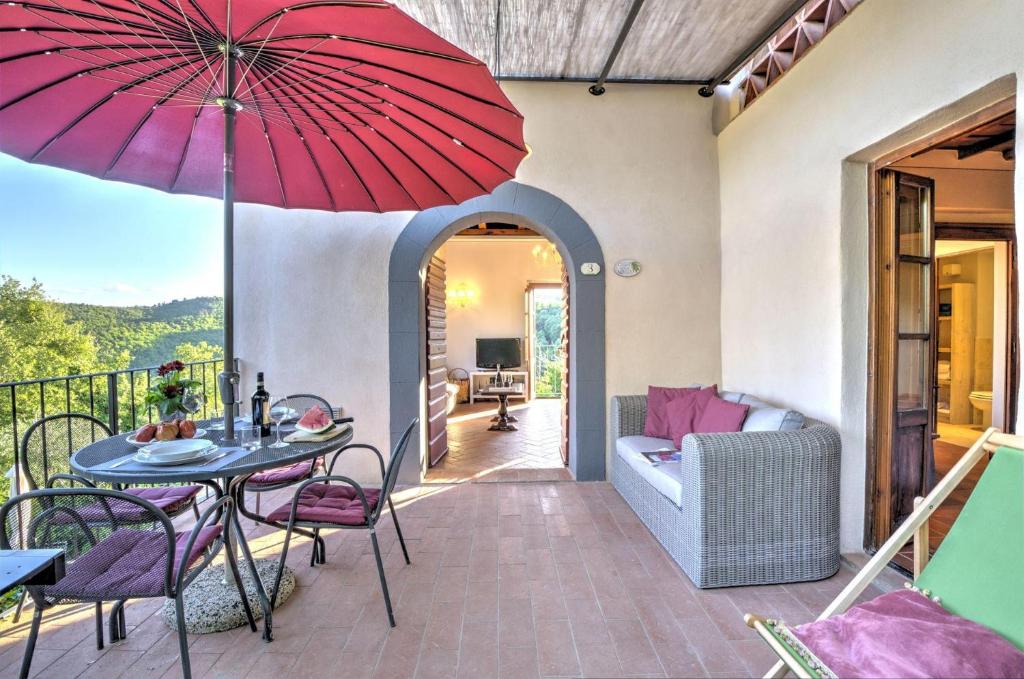 um pátio com uma mesa e um guarda-chuva vermelho em Casa della Nonna C em Gaiole in Chianti