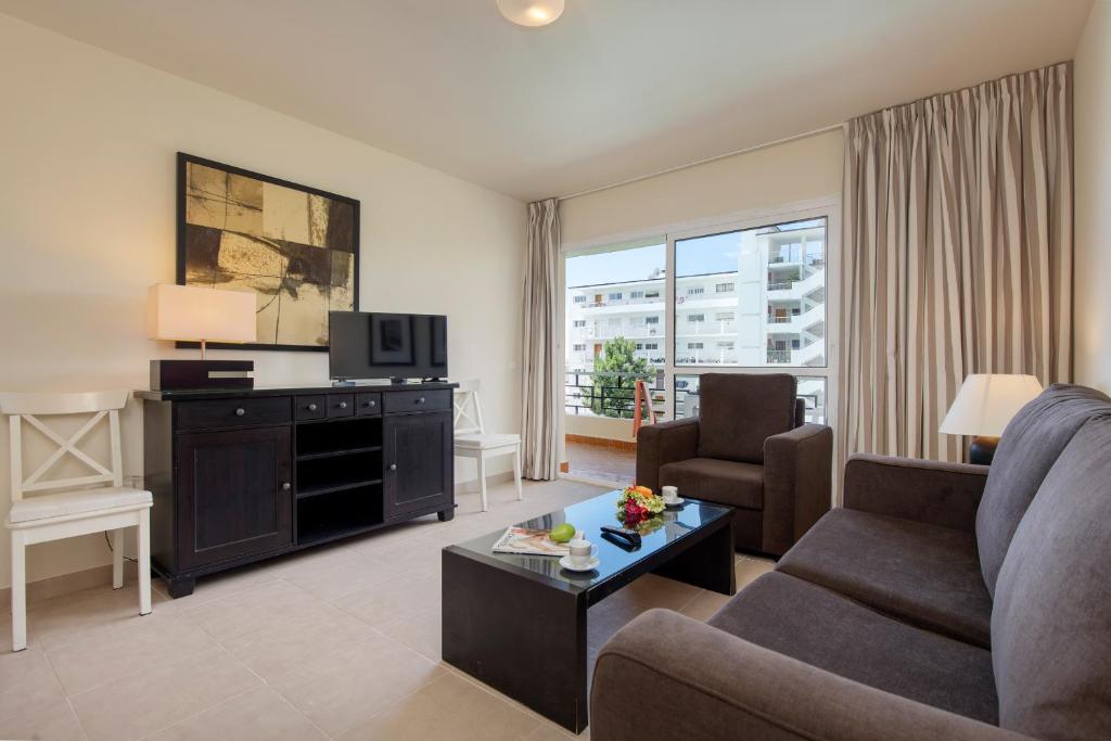 ein Wohnzimmer mit einem Sofa und einem TV in der Unterkunft Apartamentos Nucleo Cristal in Torremolinos