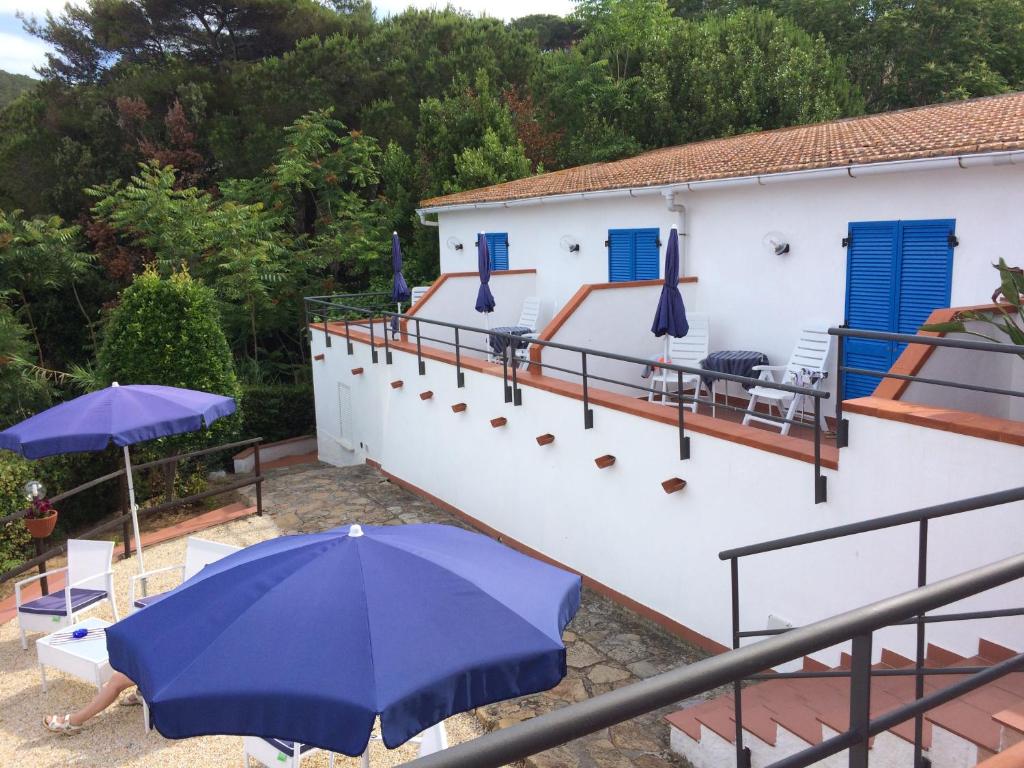 a house with a balcony with a blue umbrella at Hotel Viticcio in Portoferraio