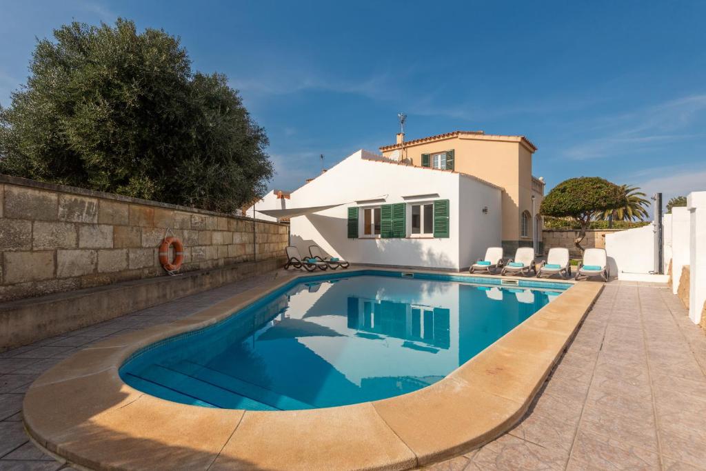 a swimming pool in front of a house at Villa Caryana in Cala en Blanes