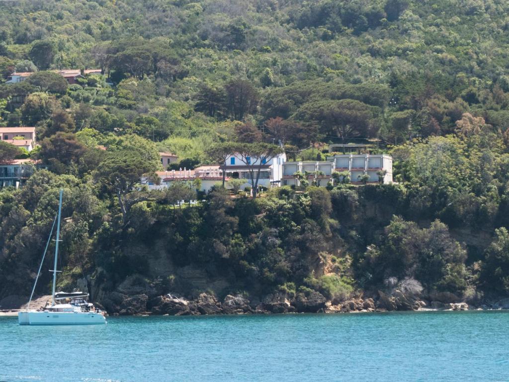 a house on a hill with a boat in the water at Hotel Viticcio in Portoferraio