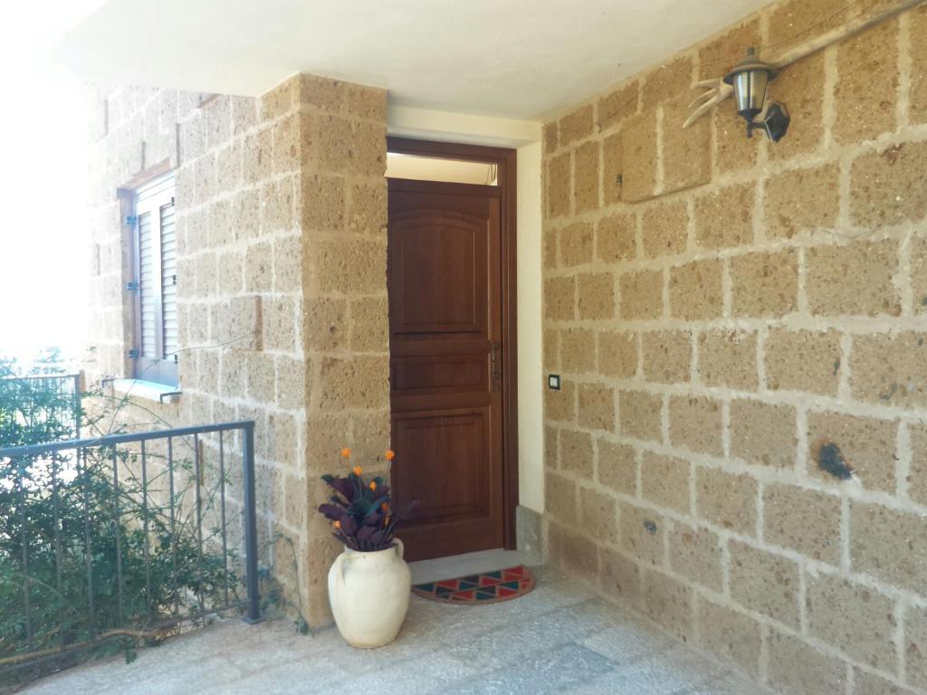 eine Tür in einer Ziegelmauer mit einer Vase daneben. in der Unterkunft Casa Francesca La Valle di Erice in Valderice