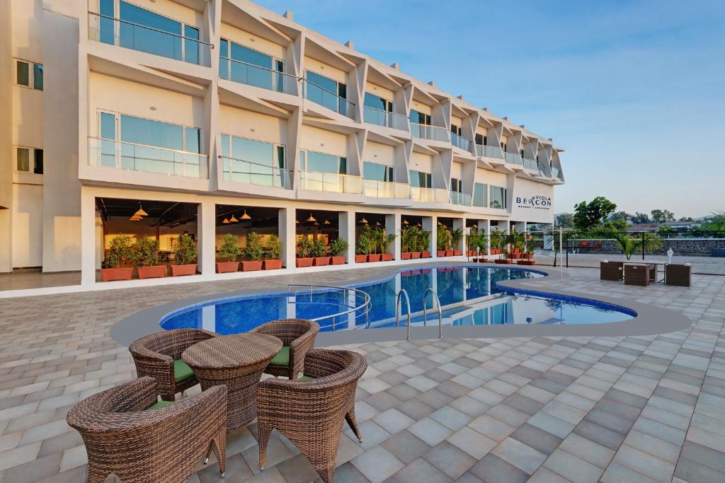 a hotel with a swimming pool in front of a building at Viola Beacon Resort, Lonavala in Lonavala