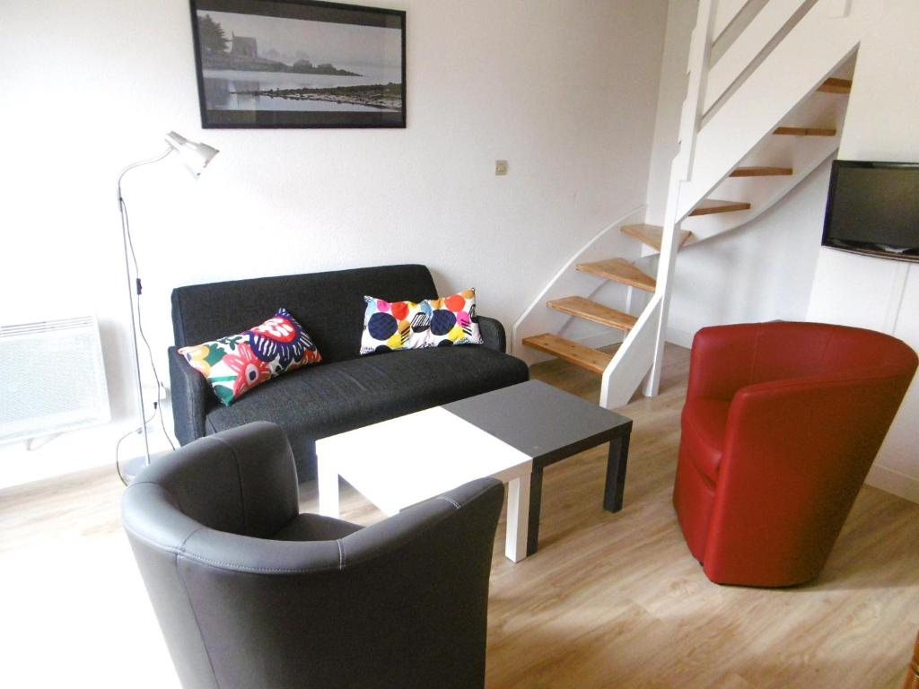 - un salon avec un canapé noir et un fauteuil rouge dans l'établissement Maisonnette Katell, à Sarzeau