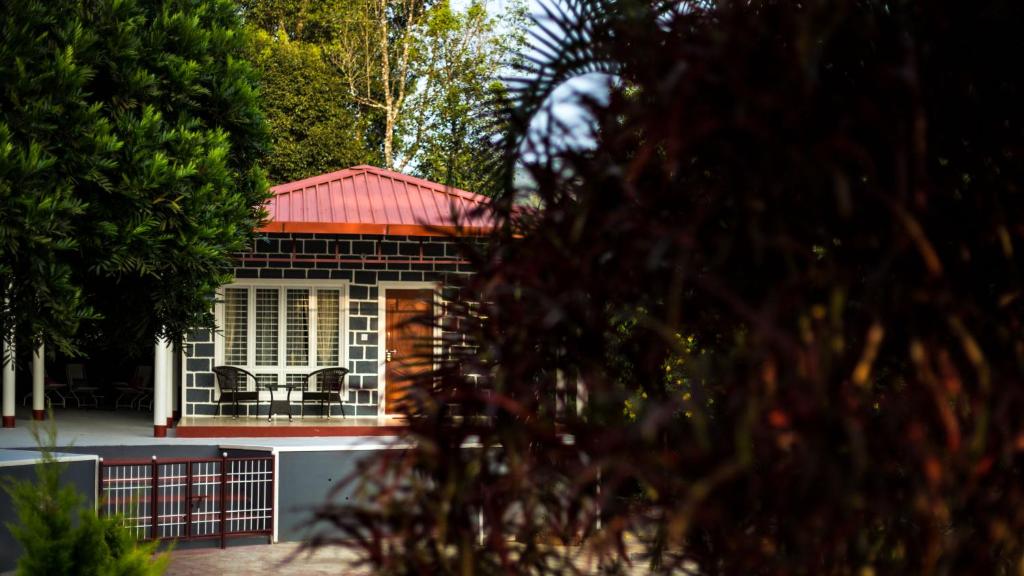 una pequeña casa con techo rojo y porche en Siddhi Aloha, en Madikeri