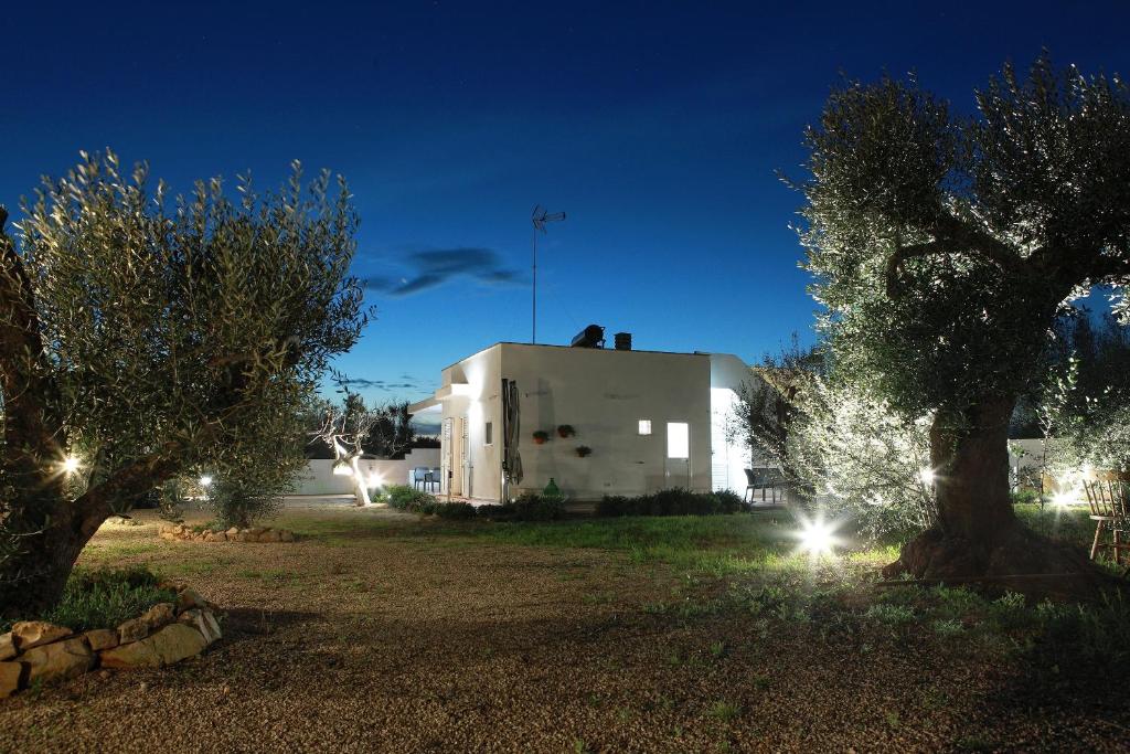 a white building with lights in a yard at night at SalentOspita Guest Rooms in Torre San Giovanni Ugento
