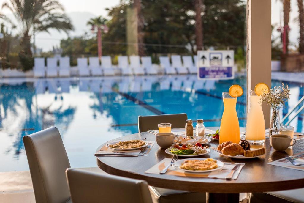 a table with food on it next to a swimming pool at Astral Nirvana Suites- Half Board in Eilat