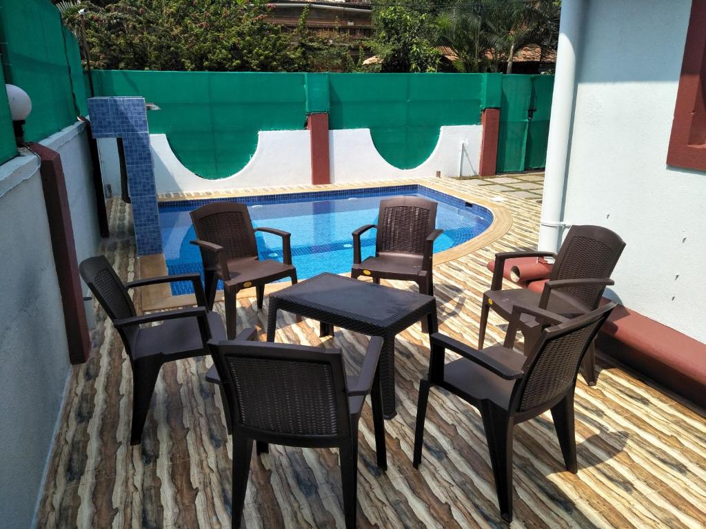 a group of chairs and a table next to a swimming pool at GR Stays - 3Bhk Private Villa in Calangute with Private Jacuzzi Pool in Calangute