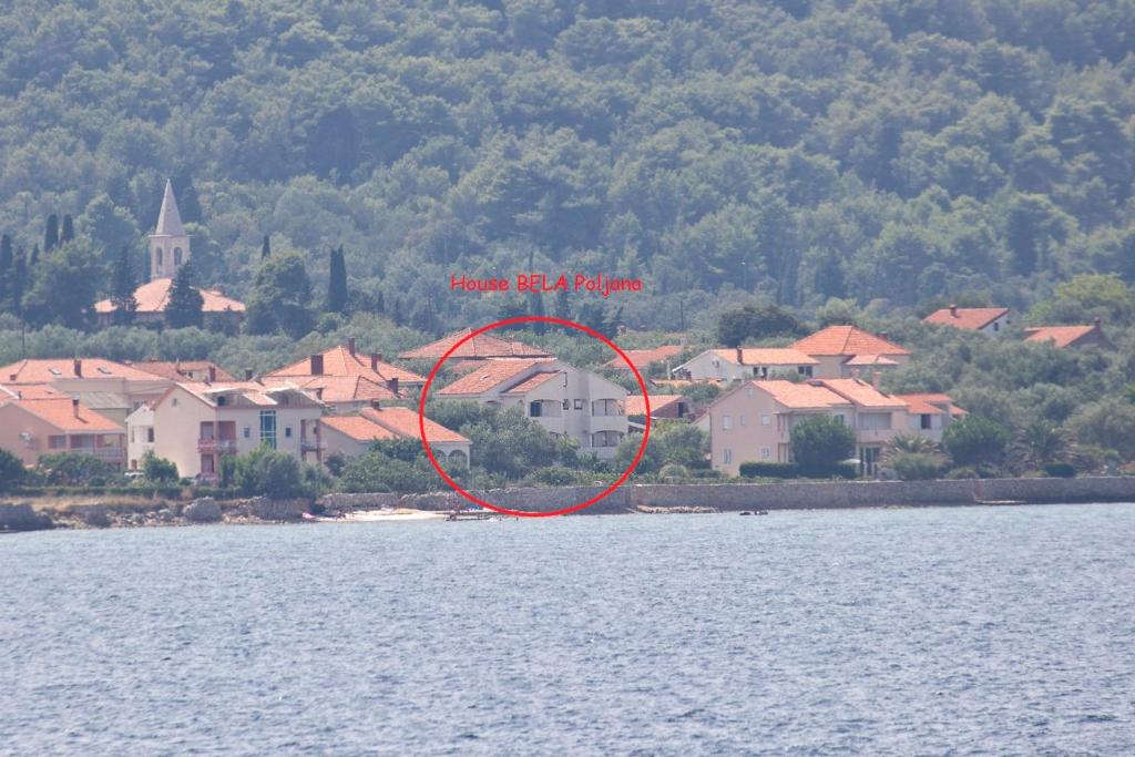 a red circle with a house in the middle of the water at Apartments Bella Poljana in Ugljan
