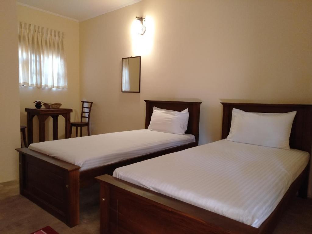 two beds sitting next to each other in a room at New Sanmi Resort in Malabe