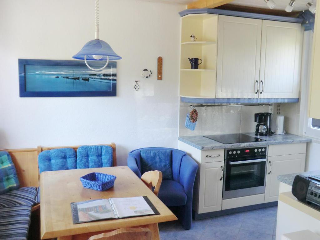 a kitchen with a table and blue chairs in a kitchen at Bungalow Ungers Welt 1 in Ostseebad Nienhagen