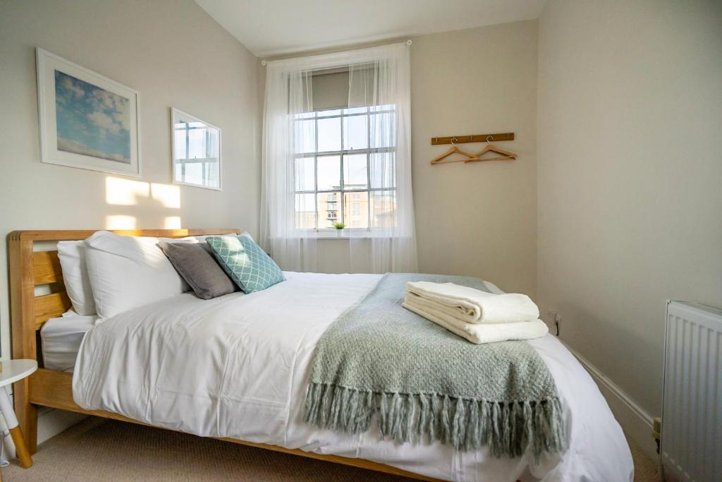 una camera da letto con un letto con lenzuola bianche e una finestra di Riverside City Loft Apartment a York