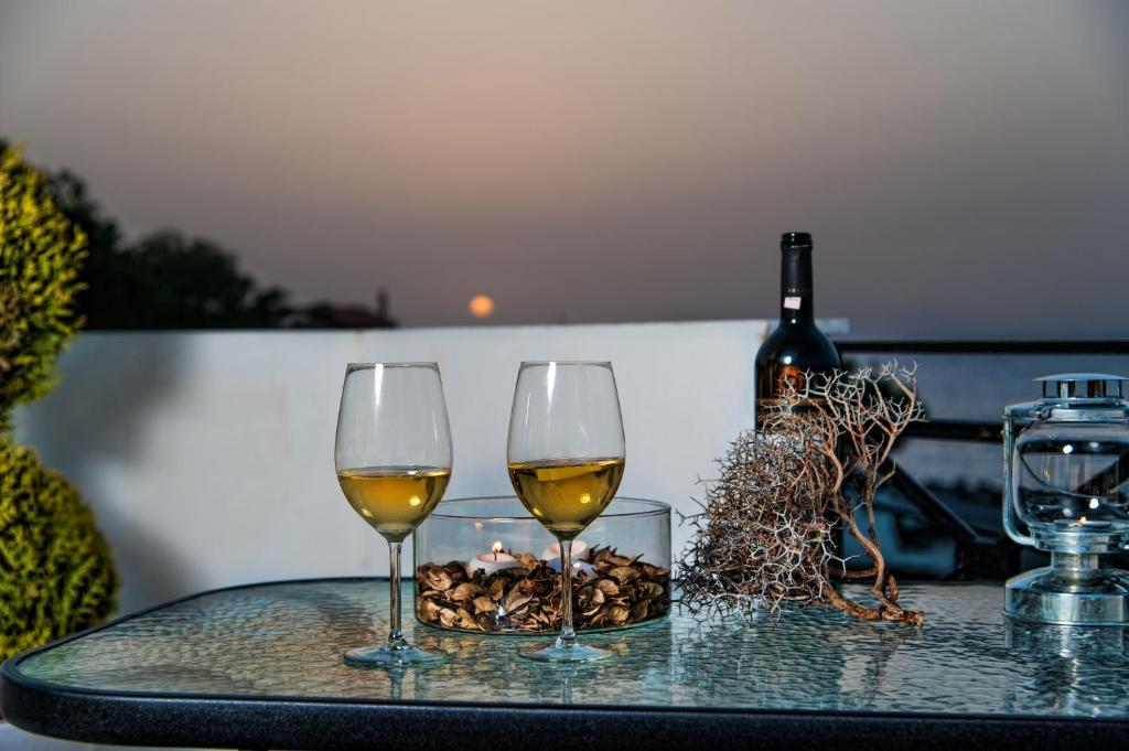 Dois copos de vinho, uma taça de nozes e uma garrafa de vinho. em Castello Apartments em Panormos - Rethymno