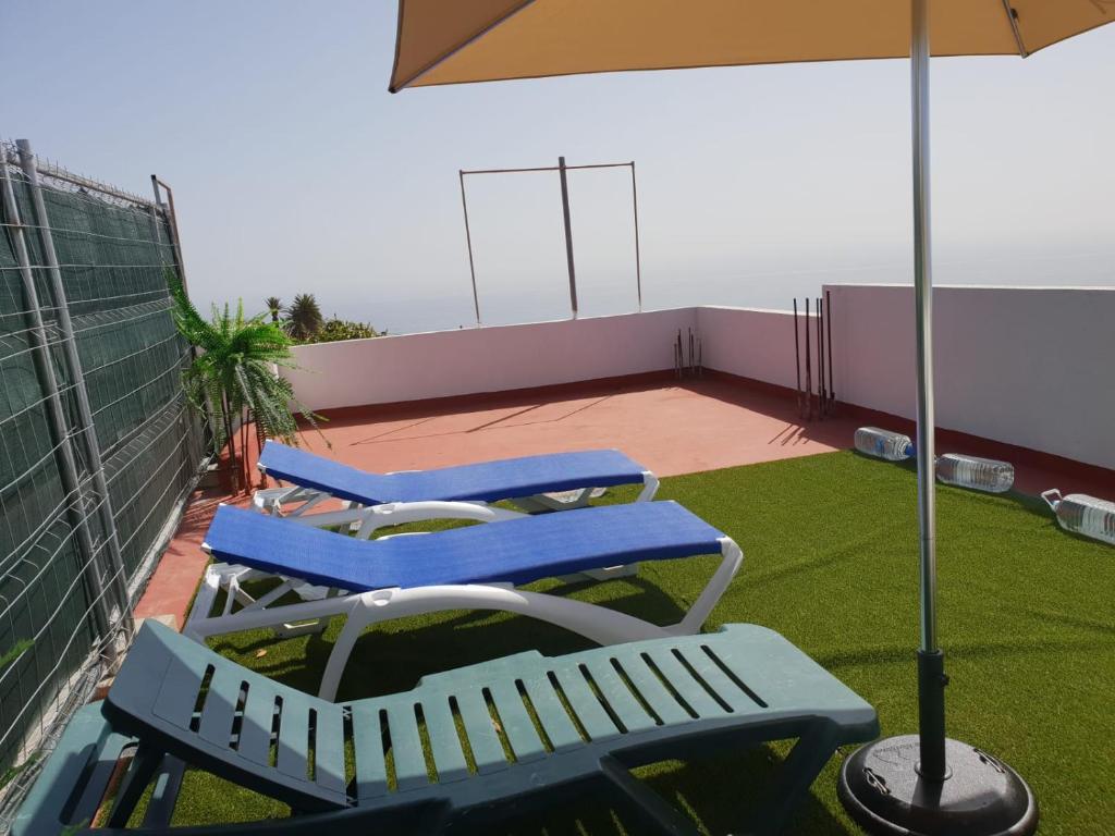 two blue chairs and an umbrella on a balcony at Casa Angel y Carmen (La Dama, La Gomera) in El Cercado