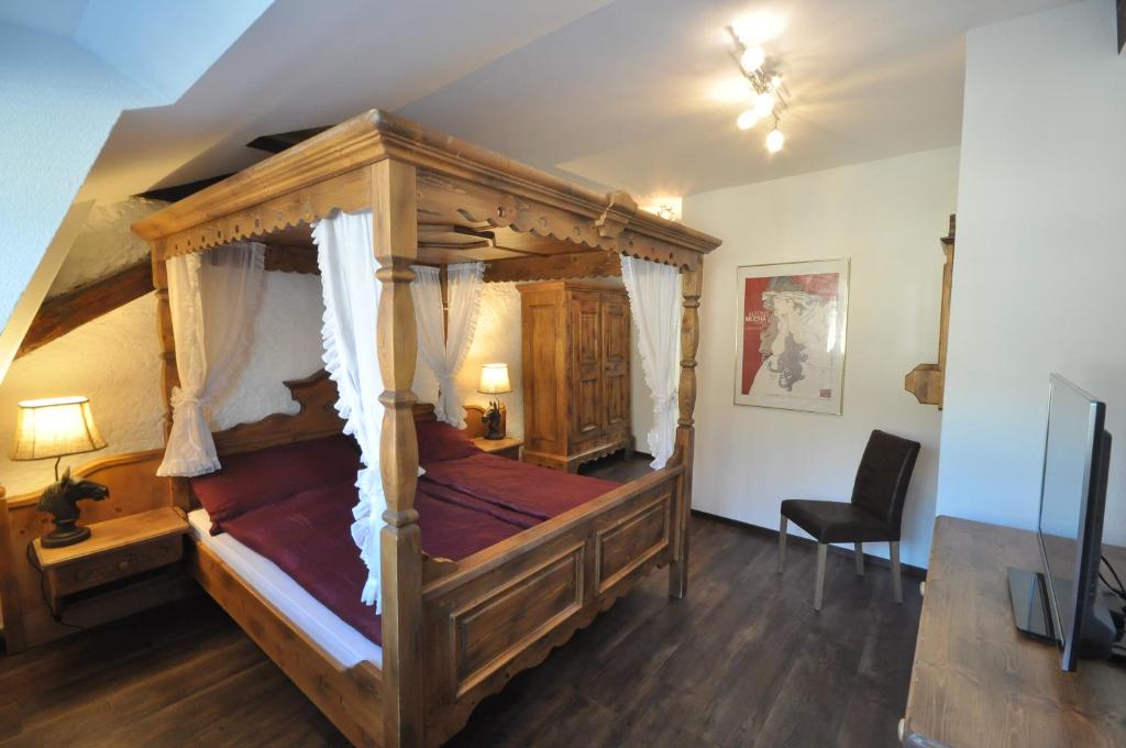 een slaapkamer met een hemelbed en een stoel bij B&B zum Rössli in Zunzgen