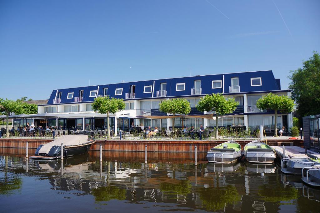 un edificio con varios barcos atracados en el agua en Fletcher Hotel Restaurant Loosdrecht-Amsterdam, en Loosdrecht