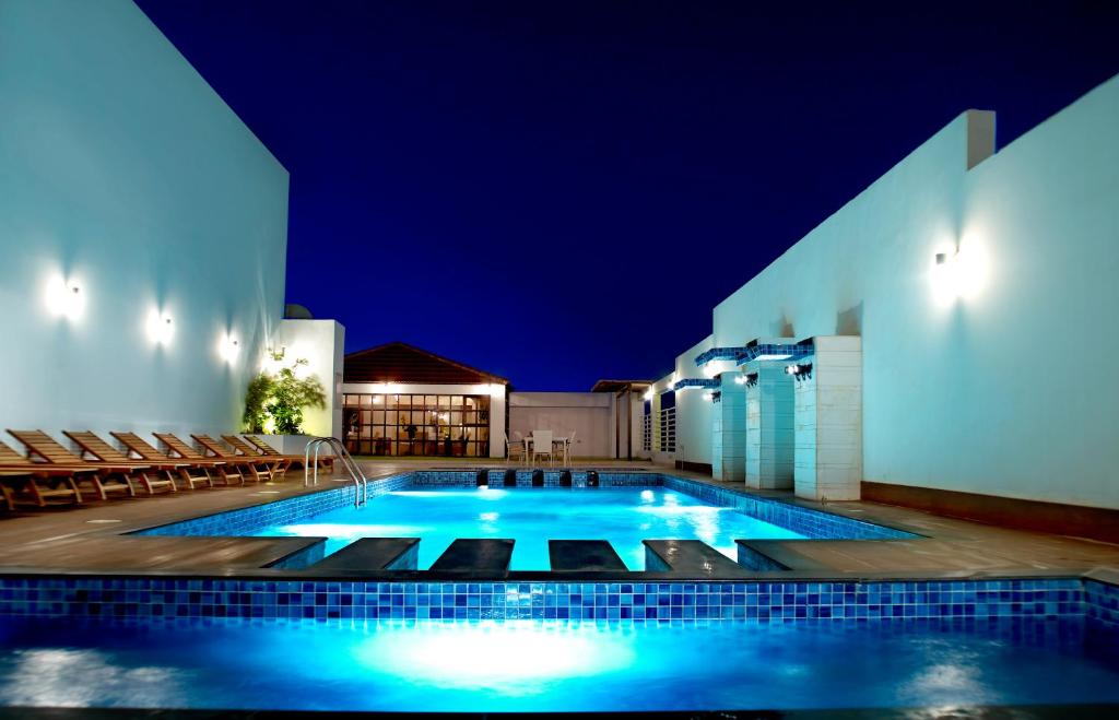 a swimming pool at night with chairs around it at Ista Suites Seef in Manama