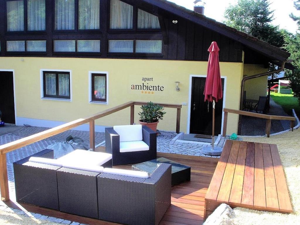 a house with a deck with a chair and an umbrella at Ferienhaus Ambiente in Ofterschwang