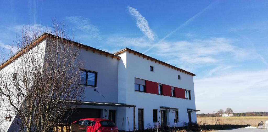 a white building with a red car in front of it at 34a Paulstraße in Postbauer-Heng