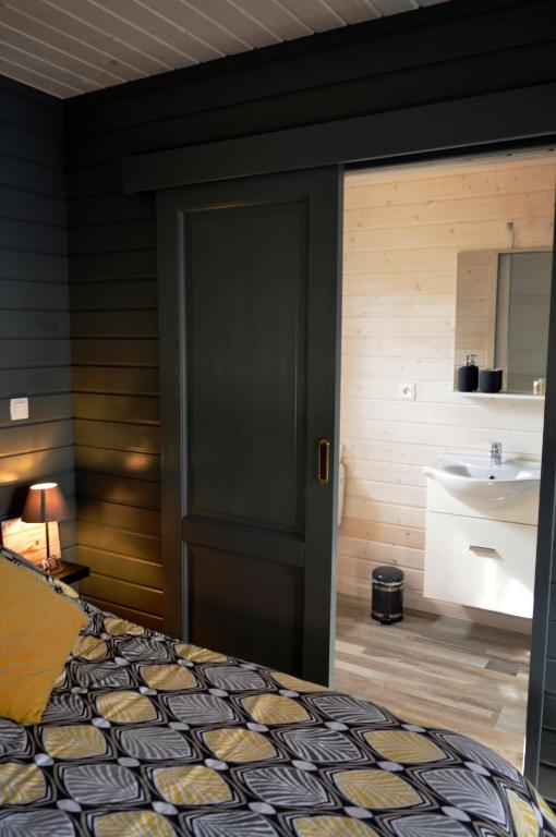 a bedroom with a bed and a bathroom with a sink at Au Cap Norwoe in Saint-Quentin-en-Tourmont