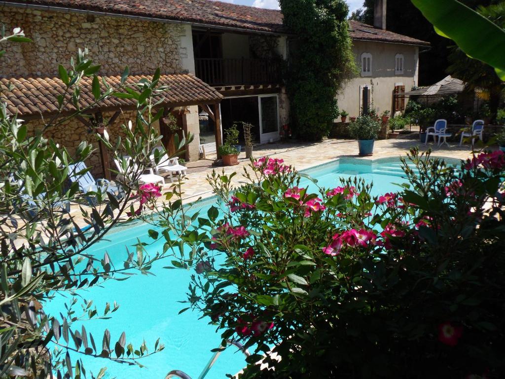 a swimming pool with flowers in front of a house at Domaine de Beaufort in Saint-Front-de-Pradoux