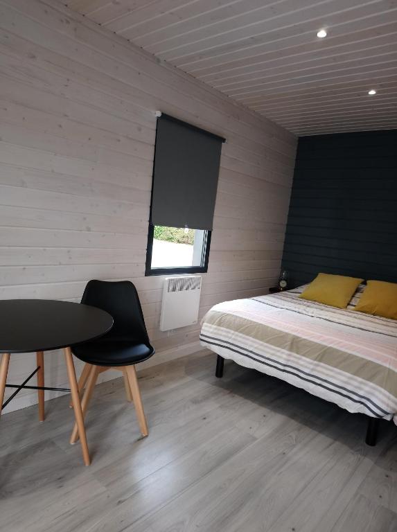 a bedroom with a bed and a table and chair at Au Cap Norwoe in Saint-Quentin-en-Tourmont