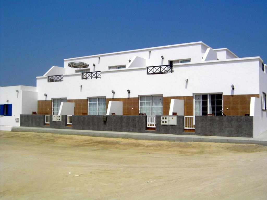 un edificio blanco con muchas ventanas en Apartamentos Graciosamar en Caleta de Sebo