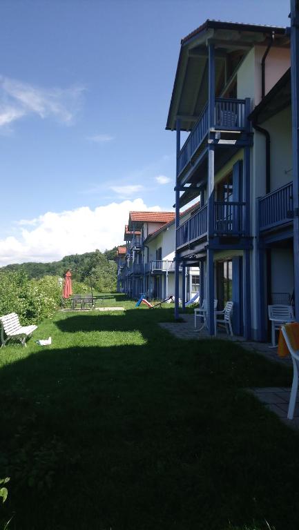 un grupo de edificios con un patio con césped y sillas en Ferienwohnanlage Sonnenwald en Langfurth 