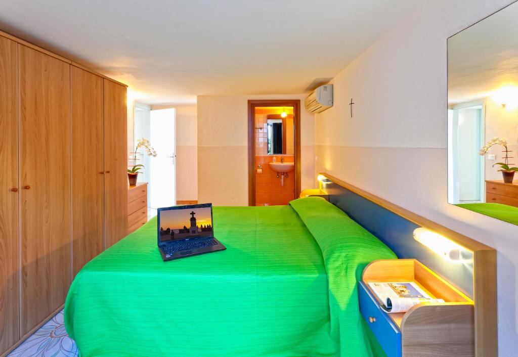 a bedroom with a green bed with a laptop on it at Casa Vacanze Parco Del Generale in Ischia