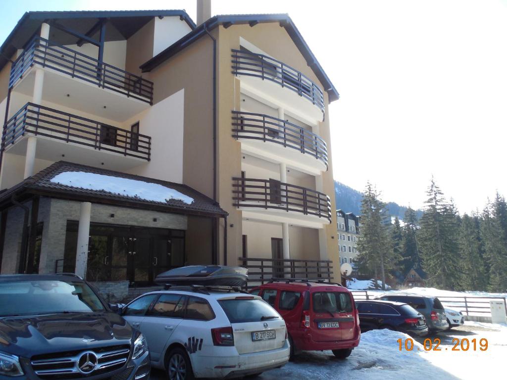 un bâtiment avec des voitures garées dans un parking dans l'établissement Ski & Bike Residence, à Poiana Brasov