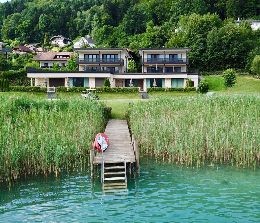 a house sitting on top of a lake with a dock at Linde Villas in Maria Wörth