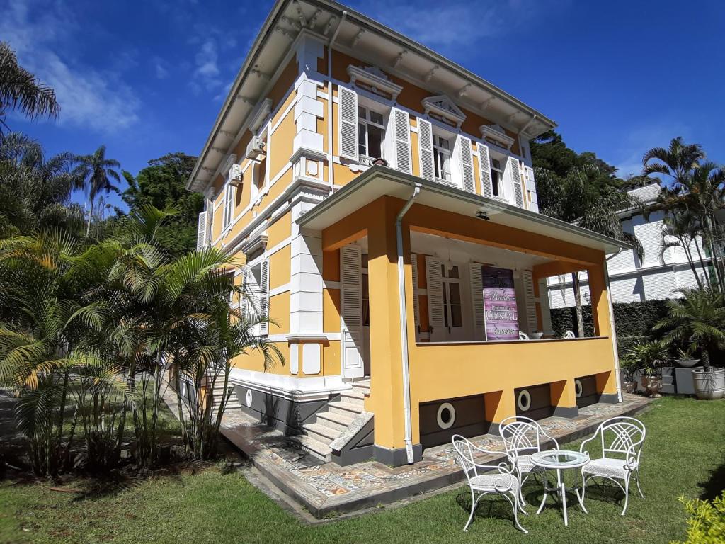 uma casa amarela e branca com cadeiras no quintal em Pousada Palacio de Cristal em Petrópolis