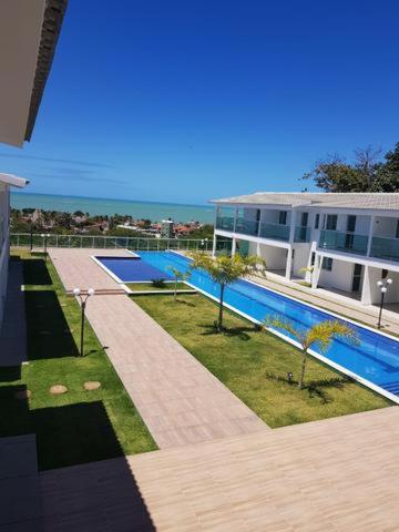 a building with a swimming pool in front of a building at Bangalô/Dúplex Jacumã Conde in Jacumã