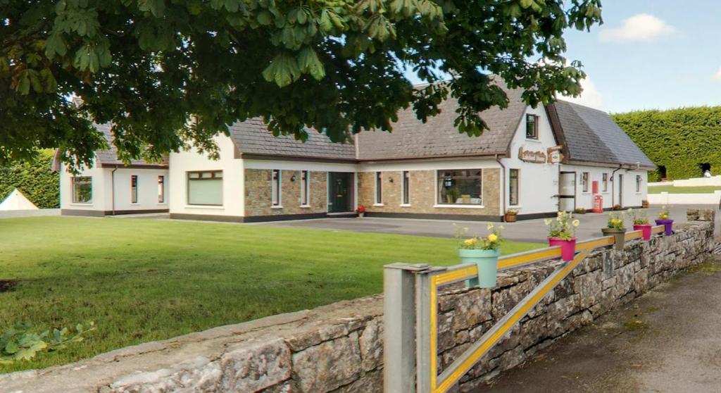 a house with a stone fence in front of it at Lakeland House in Cong