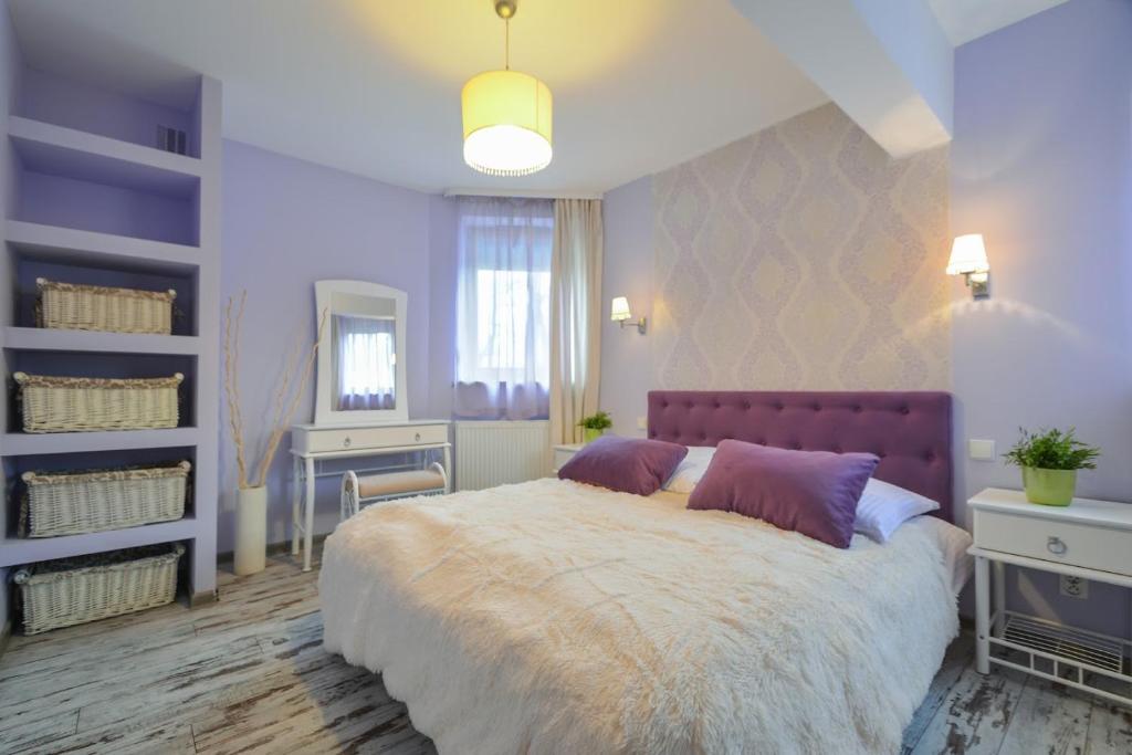a bedroom with a large bed with purple pillows at Apartament Krupówki 4 os CENTRUM in Zakopane