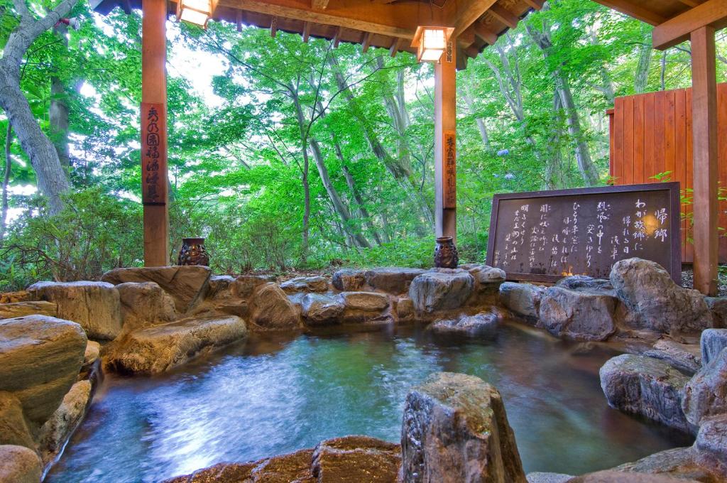 un bassin d'eau avec des rochers et des arbres dans l'établissement Ikaho Syusuien, à Shibukawa