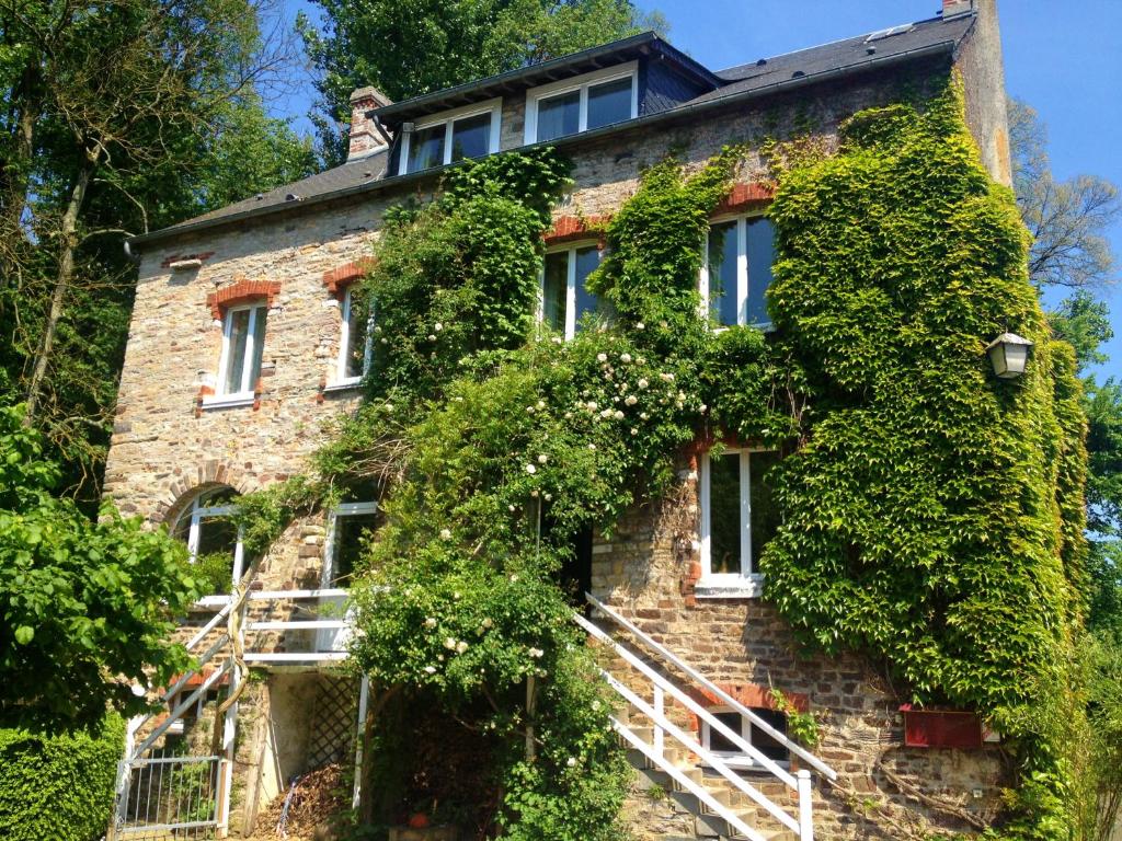 een oud stenen huis met klimop erop bij Chambres d'Hôtes du Moulin du Vey in Clécy