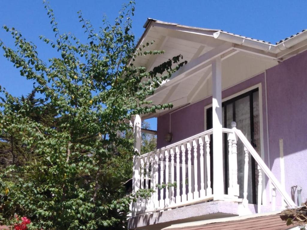 eine Veranda eines lila Hauses mit weißem Geländer in der Unterkunft Cabañas Rosy Isla Negra in Isla Negra