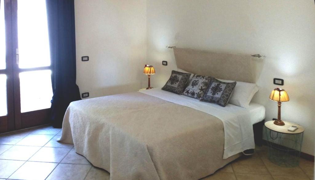 a bedroom with a large white bed with two lamps at Sa Tirìa in Chia