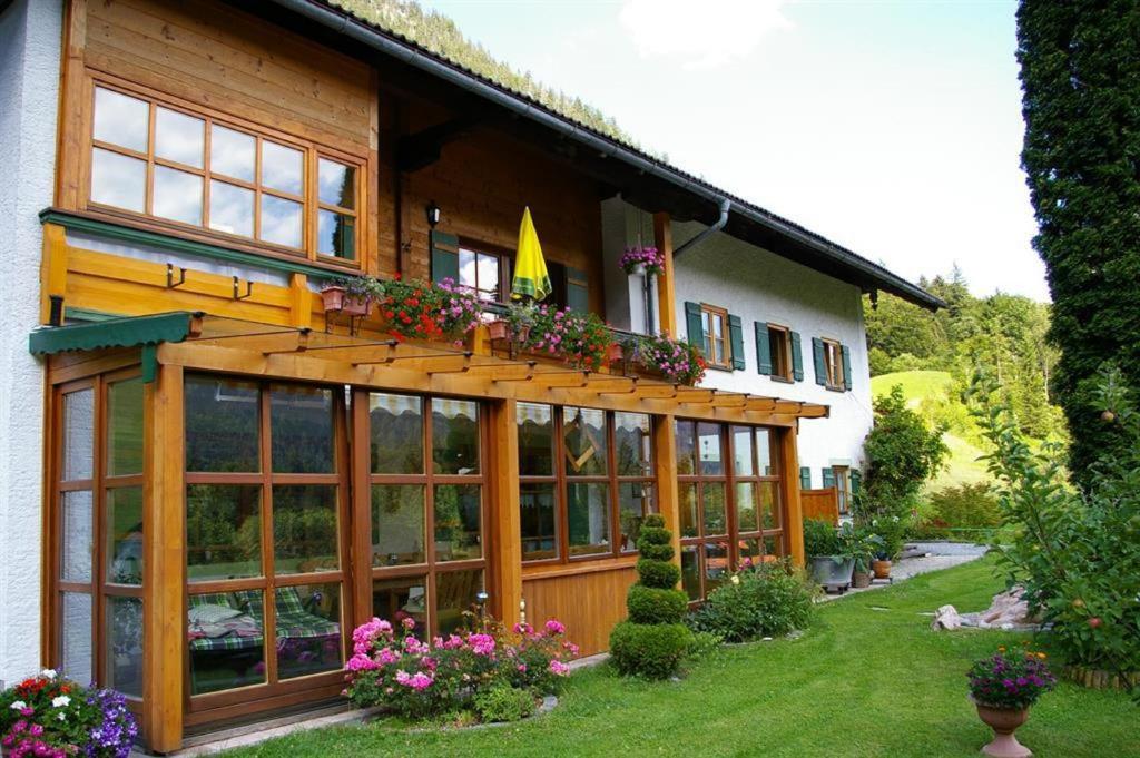 una casa con ampie finestre e un balcone fiorito di Haus Holzner-Nagl a Schneizlreuth