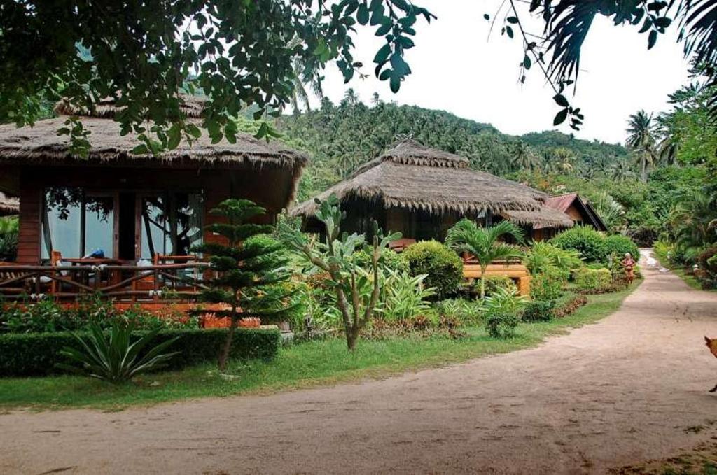 a house with a thatch roof and a road at Palm Leaf Resort Koh Tao in Ko Tao